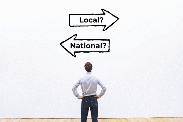 Man standing with hands on hips, facing two arrows labeled 'Local?' and 'National?' symbolizing a choice between local and national security providers.