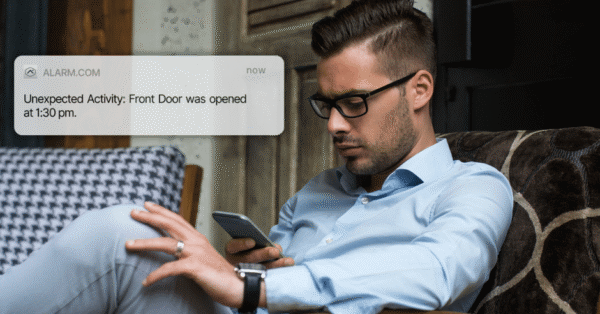 Alarm system notification showing front door unexpectedly opened, with homeowner checking phone.