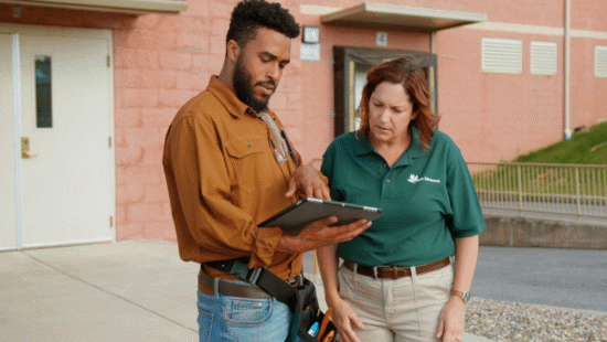 Certified technician showing a business owner security system details on a tablet.