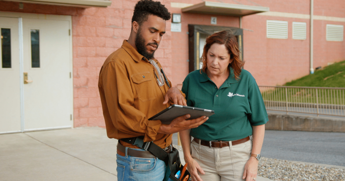 Certified technician showing a business owner security system details on a tablet.