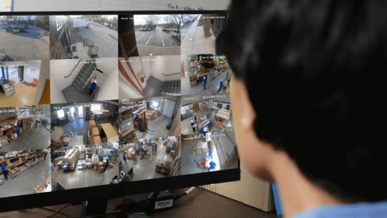 Business owner monitoring multiple security camera feeds on a computer screen, showcasing 24/7 surveillance in a commercial environment.