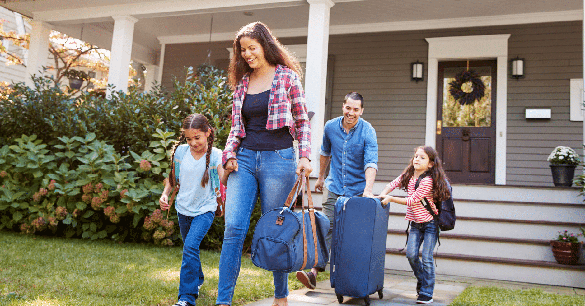 Happy family with young children leaving home with luggage, preparing for a vacation.