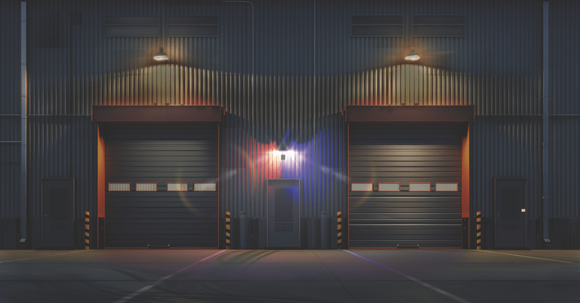 Exterior view of an industrial facility at night with bright security lighting above doors to deter intrusions.