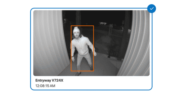 Black-and-white security camera footage showing an intruder in a hoodie highlighted by a detection box. The camera displays the location 'Entryway V724X' and timestamp '12:08:15 AM,' illustrating how video verification works to confirm emergencies.