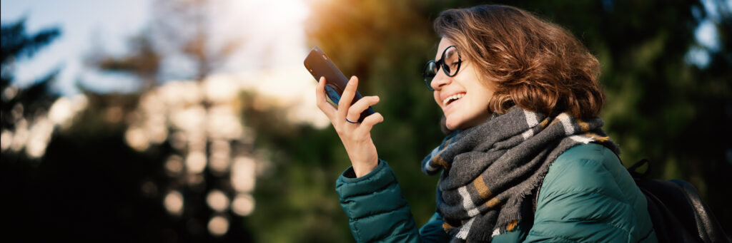 Young woman with the MyGuardianAlarm mobile app, where she can arm her security system, watch live or recorded camera footage, adjust your smart thermostat, and more.